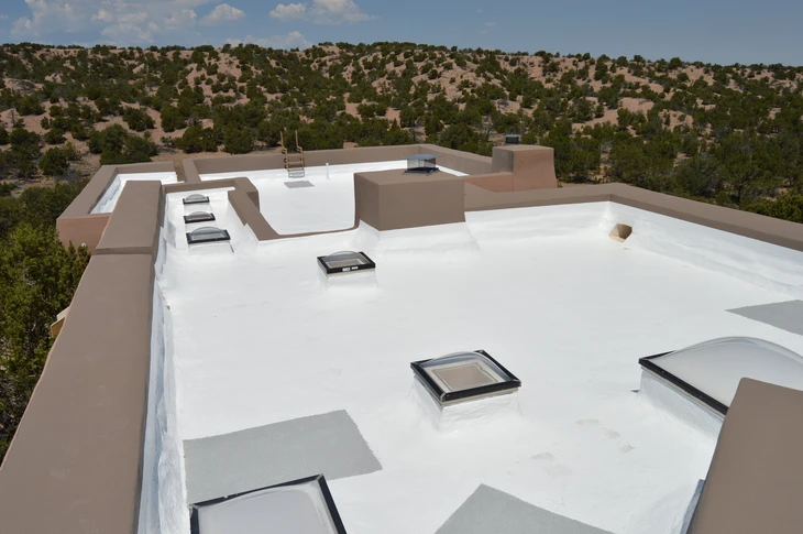 Toiture terrasse industrielle en membrane blanche étanche sous ciel nuagé
