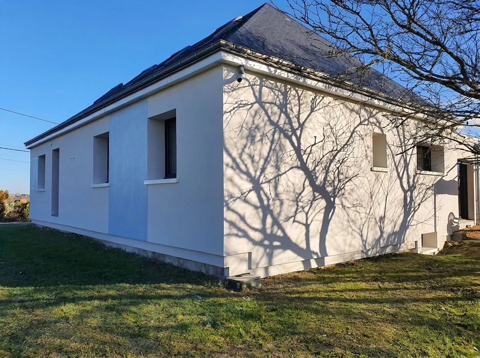Maison individuelle de plain-pied, vue extérieure angle, façade enduit blanc lisse, toiture à quatre pans en tuiles ardoise