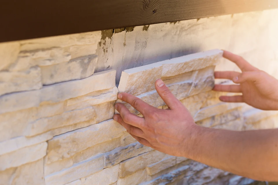 Mur en parement de pierre naturelle beige avec finition éclatée, assemblage en opus romain irrégulier créant un relief tridimensionnel