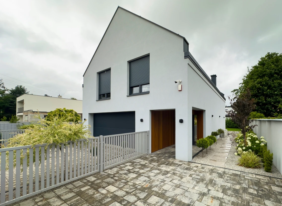 Main à l'extérieur appliquant enduit sur mur blanc avec platoir près d'une fenêtre à cadre bois