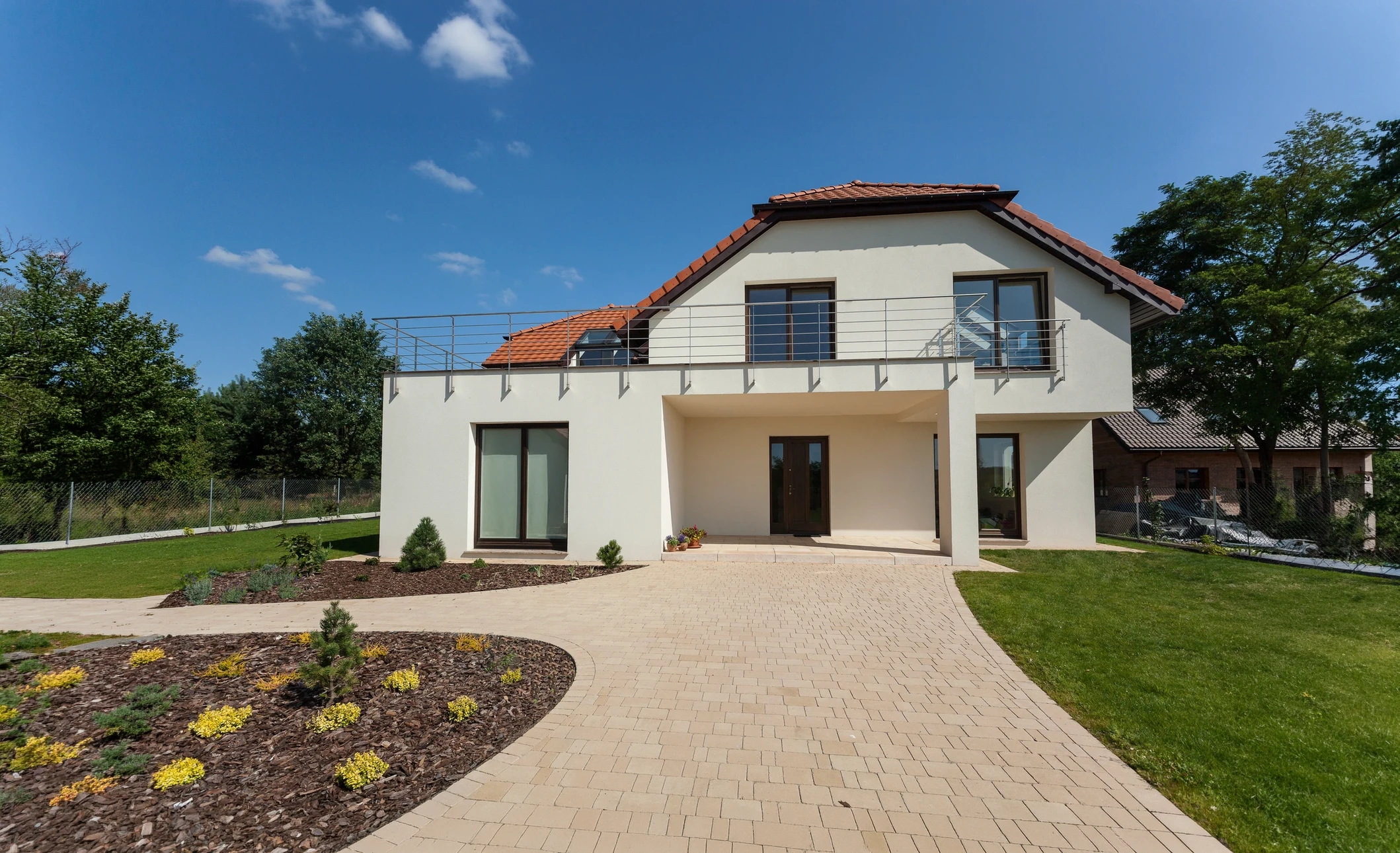 Maison contemporaine individuelle à étage avec façade enduite blanche, toiture tuiles terre cuite, balcon métallique à l'étage