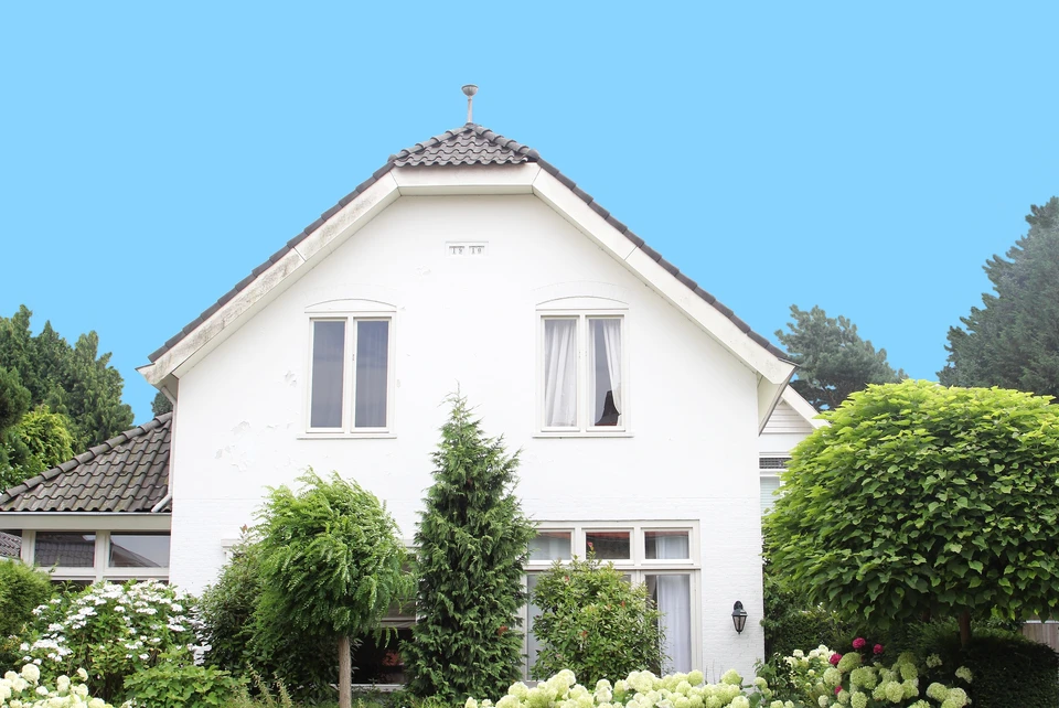 Façade extérieure d'un bâtiment avec mur en crépi rose saumon présentant des fissures et imperfections
