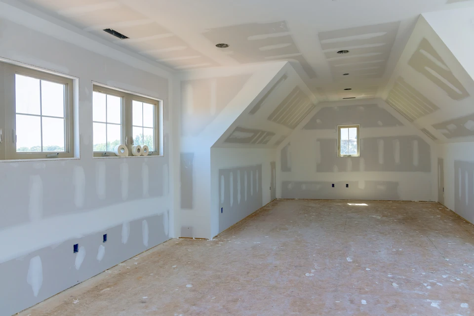 Intérieur de maison en construction avec plafond à caissons géométriques et cloisons en cours de finition
