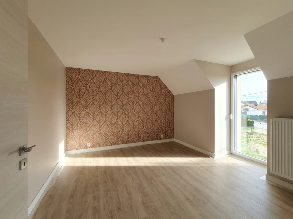 Peintre professionnel appliquant une peinture blanche ou de couleur sur un mur intérieur avec un rouleau de peinture, montrant la technique de travail soignée et précise. La scène se déroule dans un intérieur en rénovation avec des surfaces bien préparées, illustrant la maîtrise technique et le soin apporté à la finition des travaux de peinture intérieure.